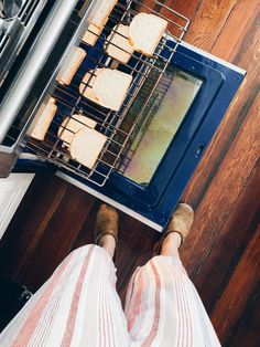 a person standing in front of an oven with food cooking on it