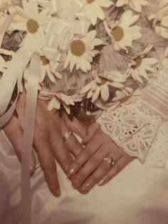 a woman's hand holding a bouquet of daisies on her wedding day,