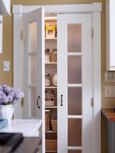 an open pantry door in a kitchen next to a counter top with baskets on it