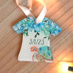 a ceramic ornament hanging on a table with a white ribbon and some blue flowers