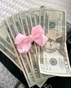 a purse filled with money and a pink bow