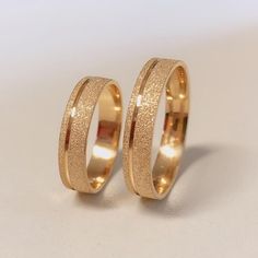 two gold wedding rings sitting next to each other