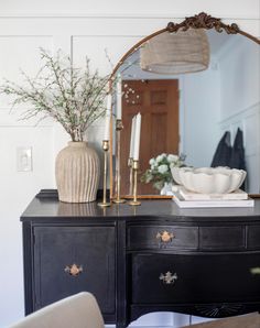 An antique French buffet painted black with a gold mirror and some books, florals, and candles. Dining Dresser Decor, Buffet In Bedroom, Black Vintage Buffet Sideboard, Antique Buffet Dining Room, Buffet Table In Bedroom, Decor For On Top Of Dresser, Antique Dresser In Kitchen, French Country Console Table Decor, Top Of Console Table Decor