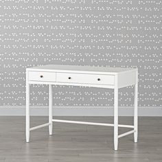 a white desk with two drawers in front of a wallpapered background that has dots on it