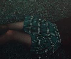 a person laying on the ground with their legs crossed wearing plaid shorts and black tights