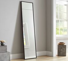 a large mirror sitting on top of a wooden floor next to a vase filled with flowers