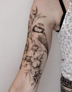 a woman's arm with a bird and flowers on it