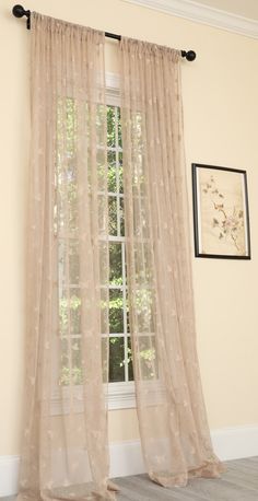 a window with sheer curtains hanging from it's side in front of a painting on the wall