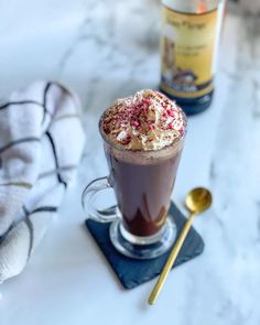 hot chocolate with whipped cream and sprinkles in a glass on a table