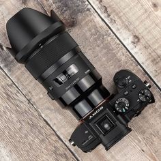 a camera and lens sitting on top of a wooden table next to it's hood