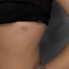 a woman with a small heart tattoo on her stomach