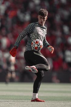 a soccer player is running with the ball in his hand while wearing red and white gloves