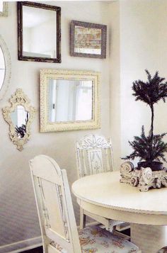 a white table with two chairs and a mirror on the wall above it is decorated with christmas decorations