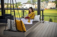 a woman sitting on a porch swing reading a book