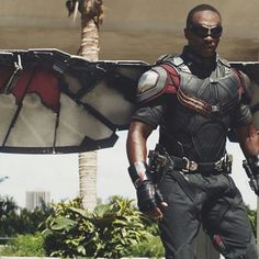 a man dressed as falcon stands in front of a palm tree