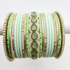 Indulge in the refreshing beauty of our Mint Green, Pearl, and Gold bangle set, designed to adorn one arm with grace and elegance. This exquisite ensemble features a collection of bangles in varying shades of mint green, offering a serene and tranquil aesthetic. The addition of lustrous pearls adds a touch of sophistication and classic charm, while the gold accents provide a radiant and opulent allure. Whether worn individually or stacked together, this bangle set adds a touch of refined glamour Green Stackable Bangle Bracelets, Green Bangle Bracelets For Wedding, Adjustable Green Bangle For Wedding, Adjustable Green Wedding Bangle, Festive Green Stackable Bracelets, Bohemian Green Bracelets For Festive Occasions, Festive Green Stackable Jewelry, Green Bangles Indian, Shades Of Mint Green