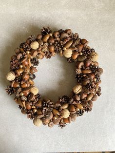 a wreath made out of pine cones and acorns sits on a white surface