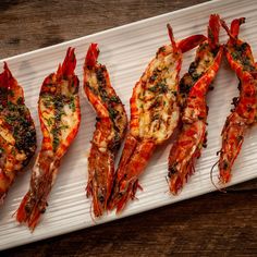 grilled shrimp on a white platter sitting on a wooden table