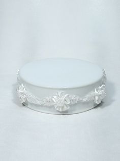 a white wedding cake plate with flowers on the rim and beaded trim around the edge