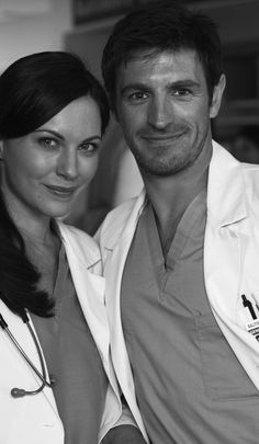 a black and white photo of a man and woman in scrubs posing for the camera