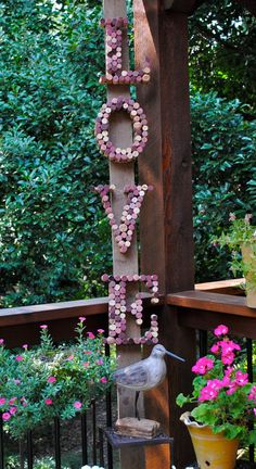 a bird sitting on top of a wooden post next to potted plants and flowers