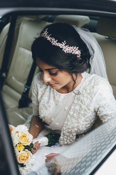 a woman in a wedding dress sitting in a car