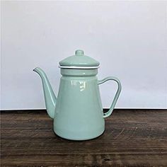 a blue teapot sitting on top of a wooden table next to a white wall