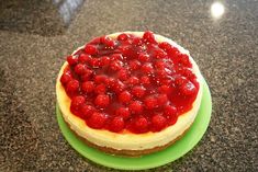 a cheesecake topped with raspberries on top of a green platter sitting on a counter