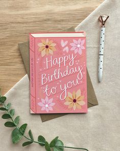 a card with the words happy birthday to you on it next to a pen and flowers