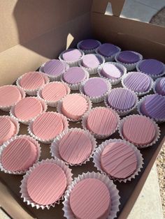 a box filled with pink and purple cupcakes sitting on top of a table