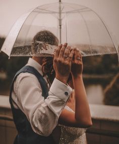 a bride and groom holding an umbrella in the rain