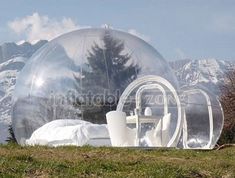 an inflatable bubble tent set up on the grass with mountains in the background