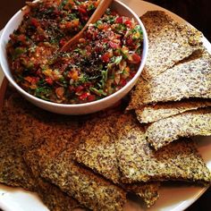 a white plate topped with tortilla chips next to a bowl filled with salsa