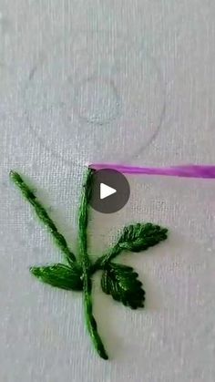 a piece of cloth with green leaves on it and a purple string in the middle