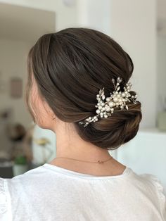 a woman wearing a hair comb with pearls on it's head and her hair in a low bun