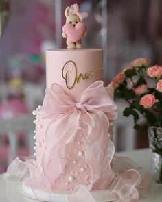 a pink cake with a teddy bear on top