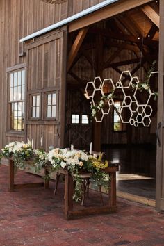 flowers and greenery are arranged in front of an open barn door with hanging honeycombs