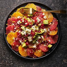 a black plate topped with fruit salad and a fork