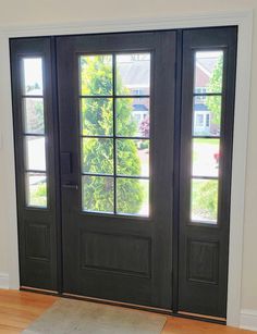 a black door with two windows and a rug on the floor in front of it