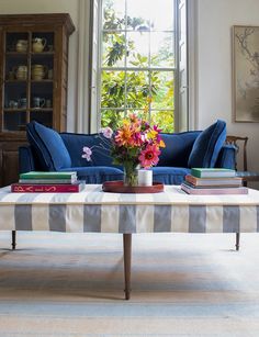 a living room with a blue couch, coffee table and books on the end tables