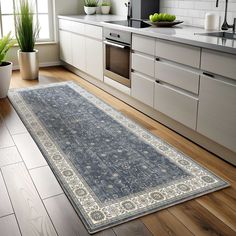 a large rug in the middle of a kitchen with white cabinets and wooden flooring