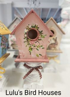 a pink bird house sitting on top of a white table next to other small houses