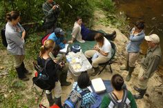 a group of people standing around a table next to a river