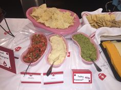 a table topped with bowls filled with different types of guacamole and tortilla chips