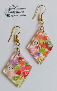 a pair of earrings with fruit designs on them