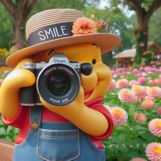 a statue of winnie the pooh holding a camera in front of some pink flowers