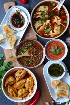 several bowls of food on a table with chopsticks and spoons next to them