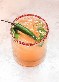 a drink with a green pepper on the rim and garnished in red flecks