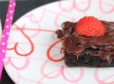 a piece of chocolate cake on a plate next to a pink strawberries and fork