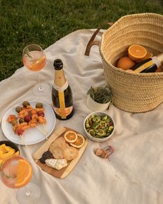 an outdoor picnic with oranges, wine and food